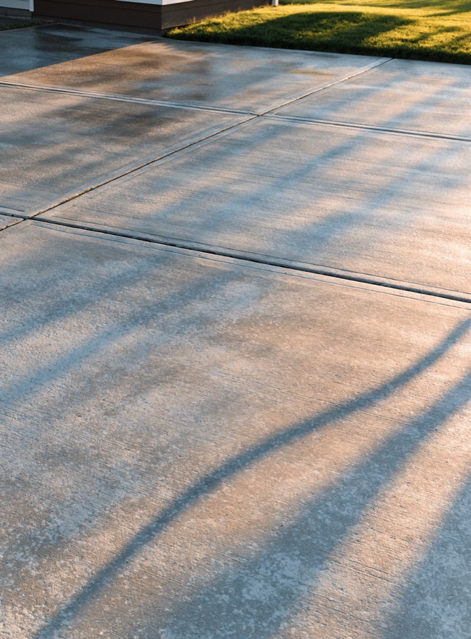 A concrete driveway cleaned back to an even tone in late-afternoon light.